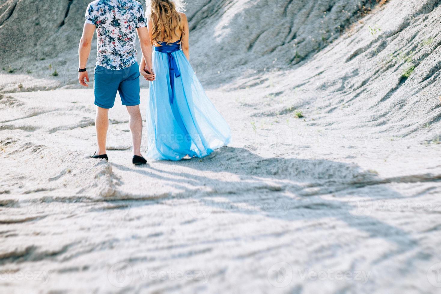 Blonde girl in a light blue dress and a guy in a light shirt in a granite quarry photo