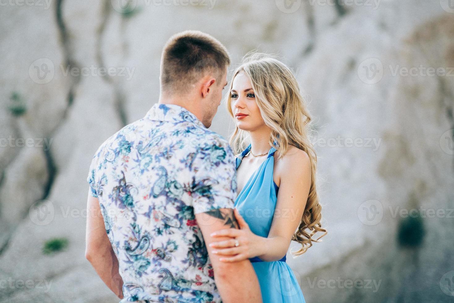 Blonde girl in a light blue dress and a guy in a light shirt in a granite quarry photo