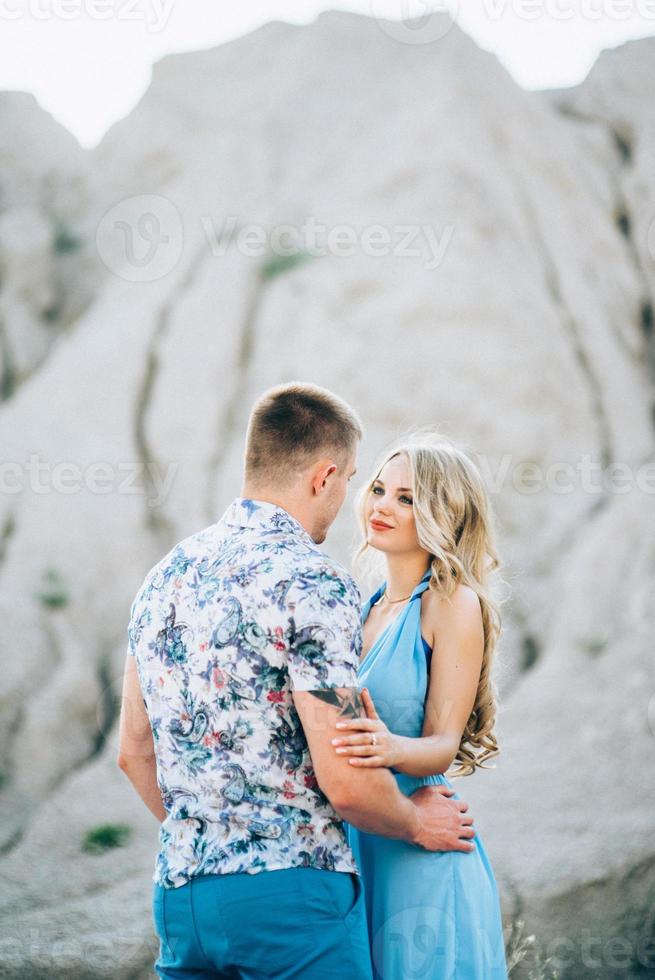 chica rubia con un vestido azul claro y un chico con una camisa ligera en una cantera de granito foto