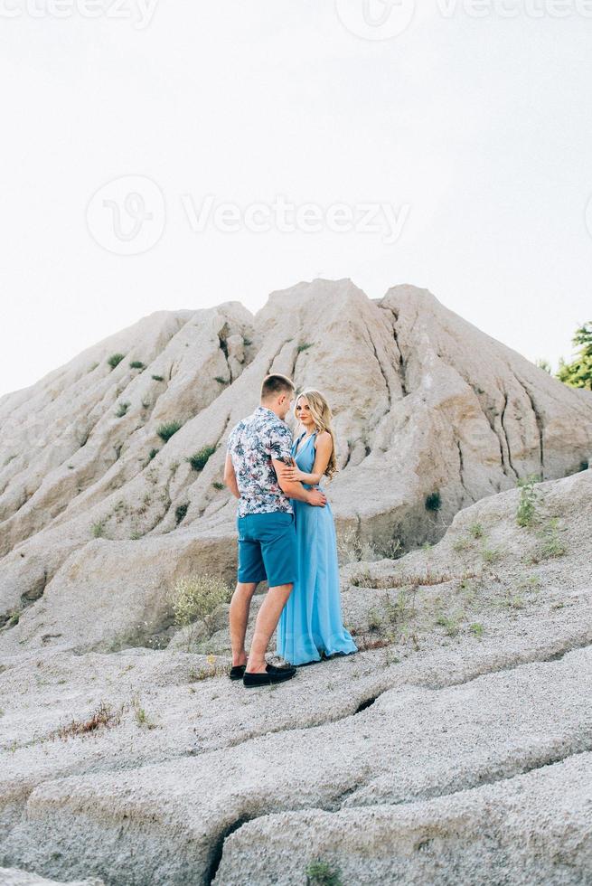 Blonde girl in a light blue dress and a guy in a light shirt in a granite quarry photo