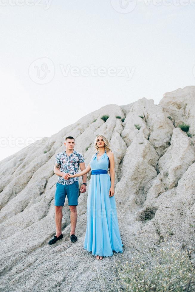 Blonde girl in a light blue dress and a guy in a light shirt in a granite quarry photo