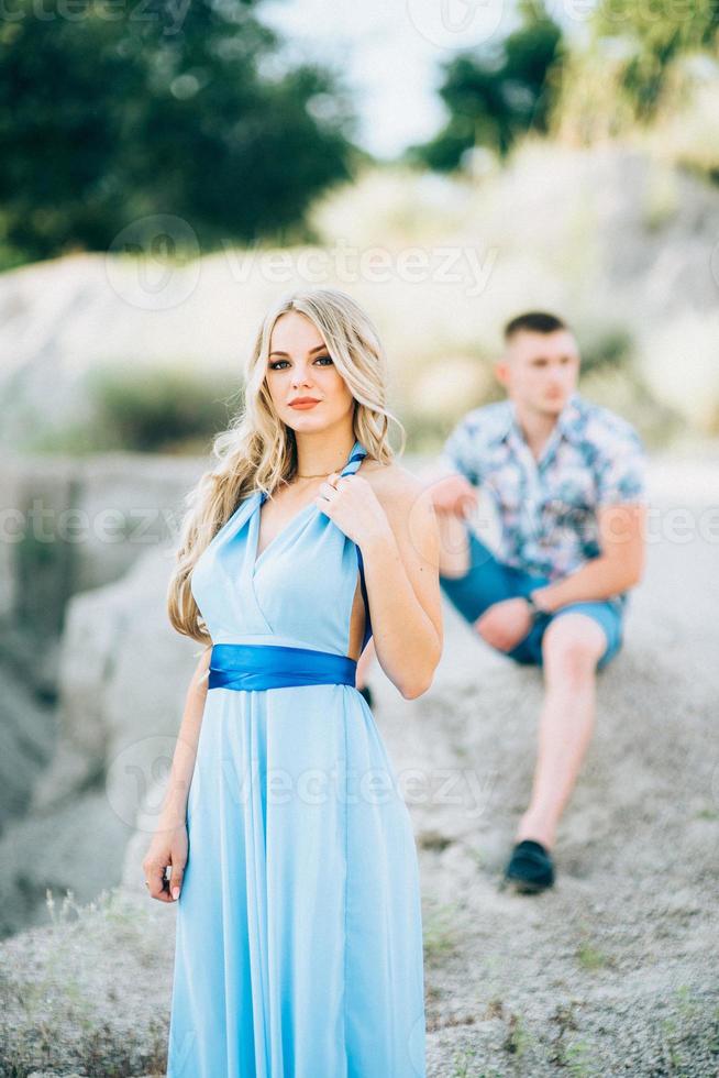 Blonde girl in a light blue dress and a guy in a light shorts in a granite quarry photo