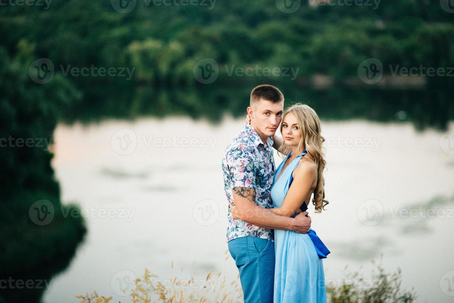 chica rubia con el pelo suelto con un vestido azul claro y un chico a la luz del atardecer foto