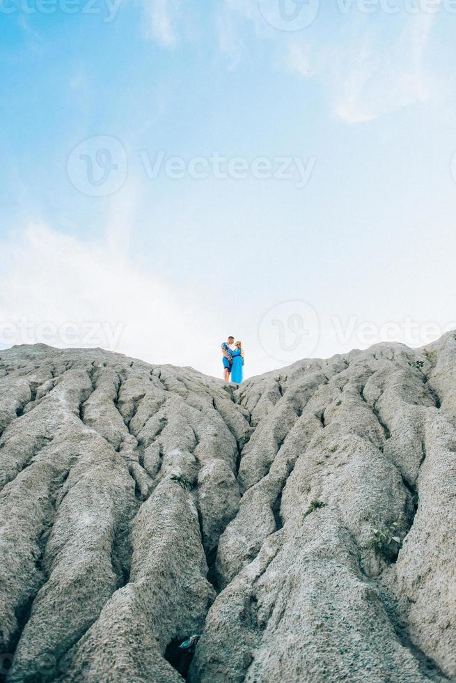 chica rubia con un vestido azul claro y un chico con una camisa ligera en una cantera de granito foto