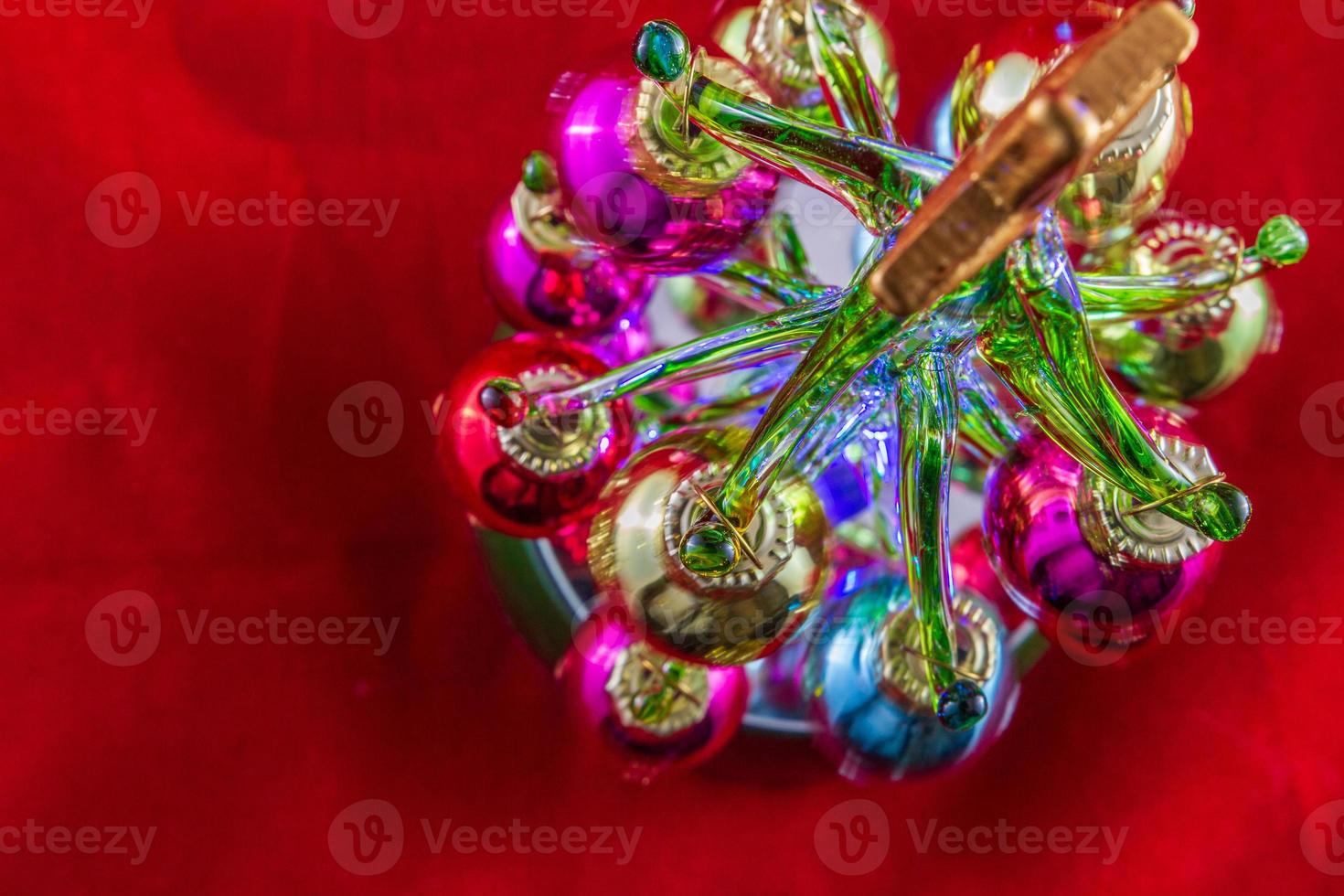 Mini Christmas tree made of glass illuminated on red background photo