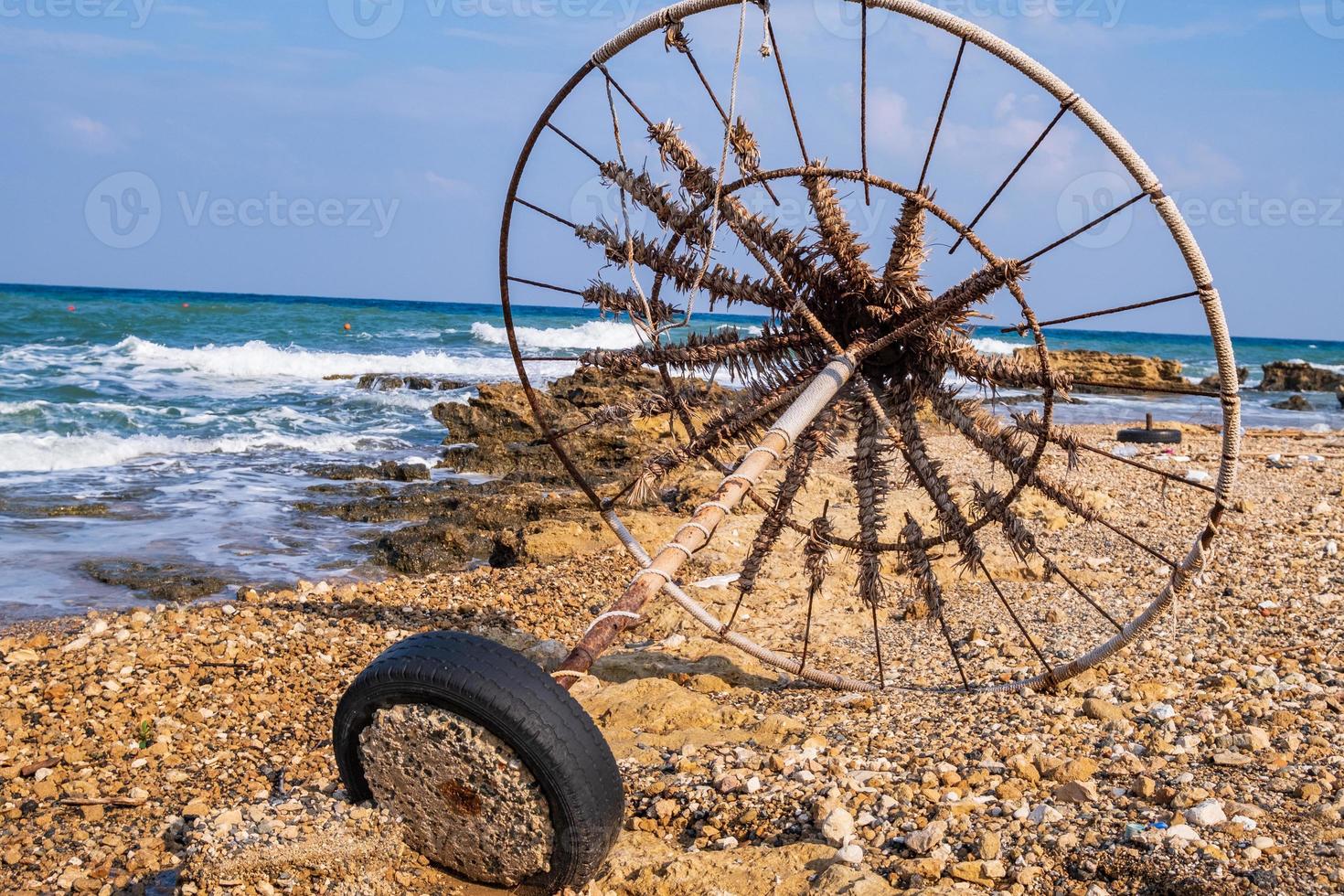 Abandoned beach umbrella on a rocky beach set against the sea photo