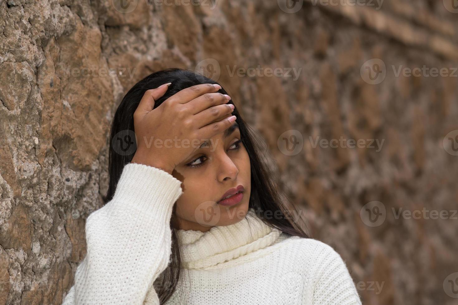 Closeup portrait of a tired brunette woman with a hand on her forehead photo