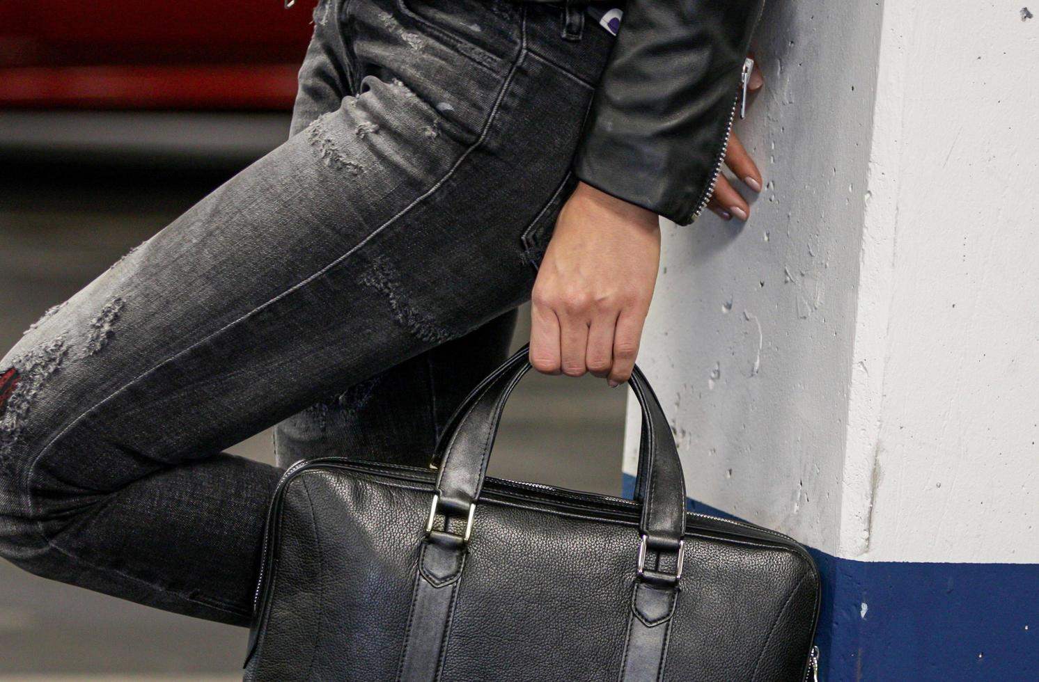 Imagen recortada de una elegante mujer sosteniendo un gran bolso de cuero negro foto