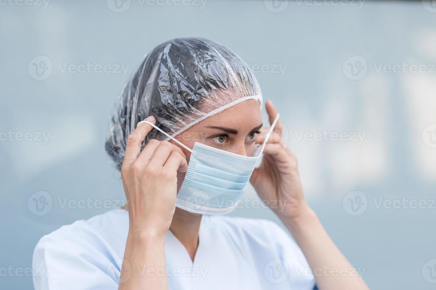 Woman doctor putting on her facial mask photo