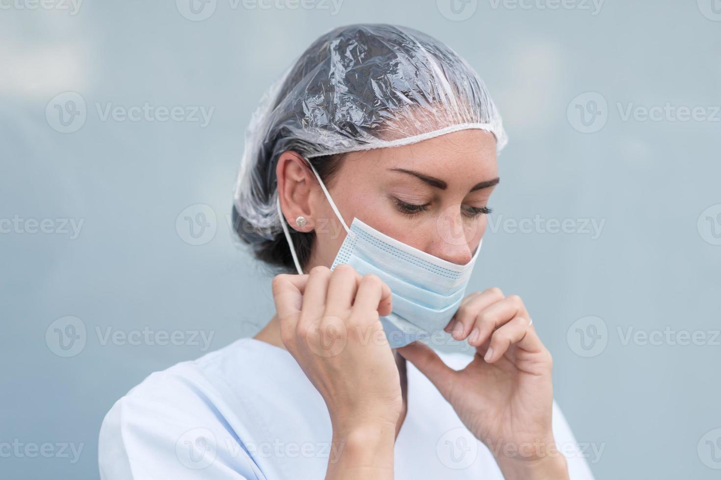 Woman doctor putting on her facial mask photo