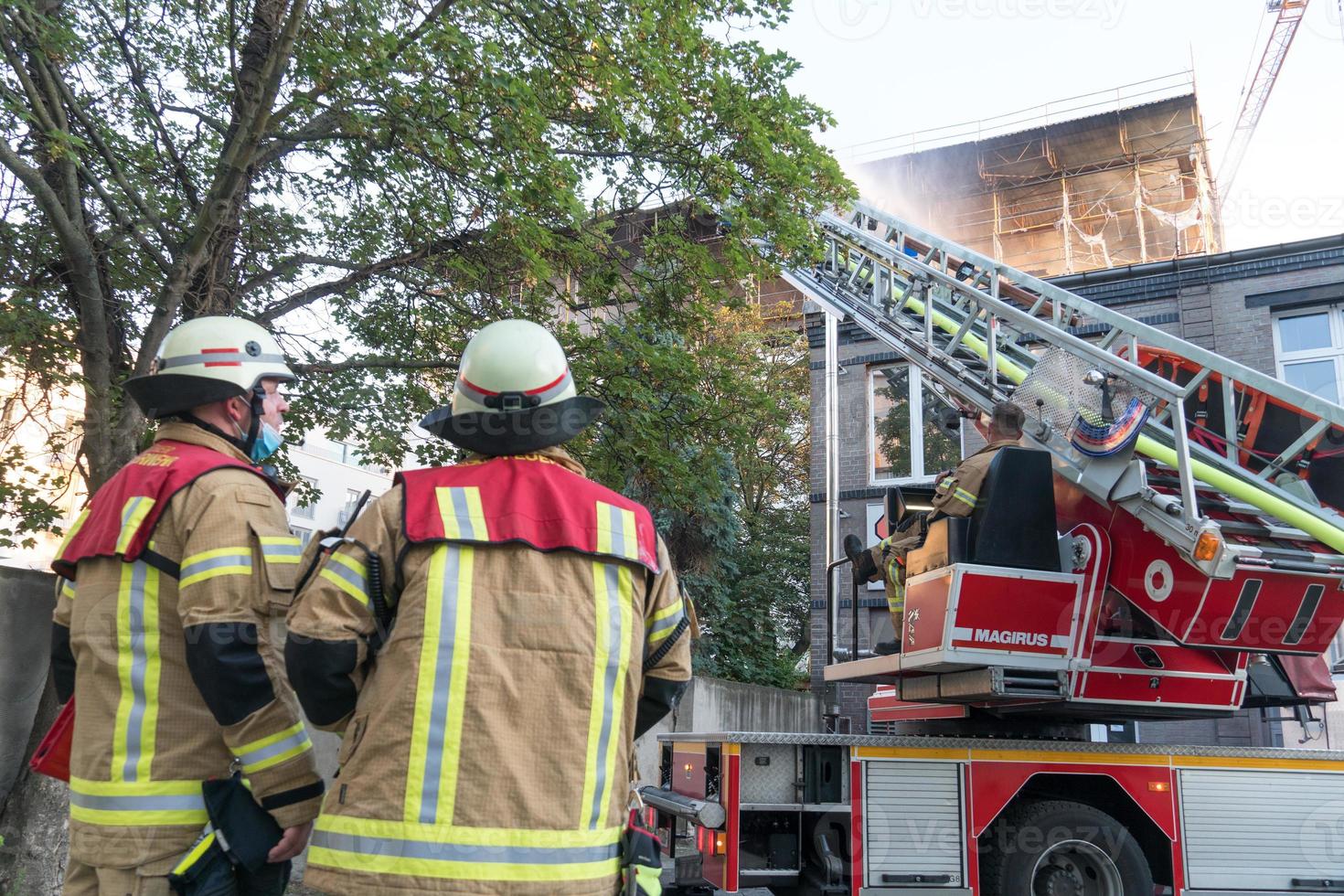 Bomberos en el trabajo extinguiendo el fuego con una escalera giratoria foto