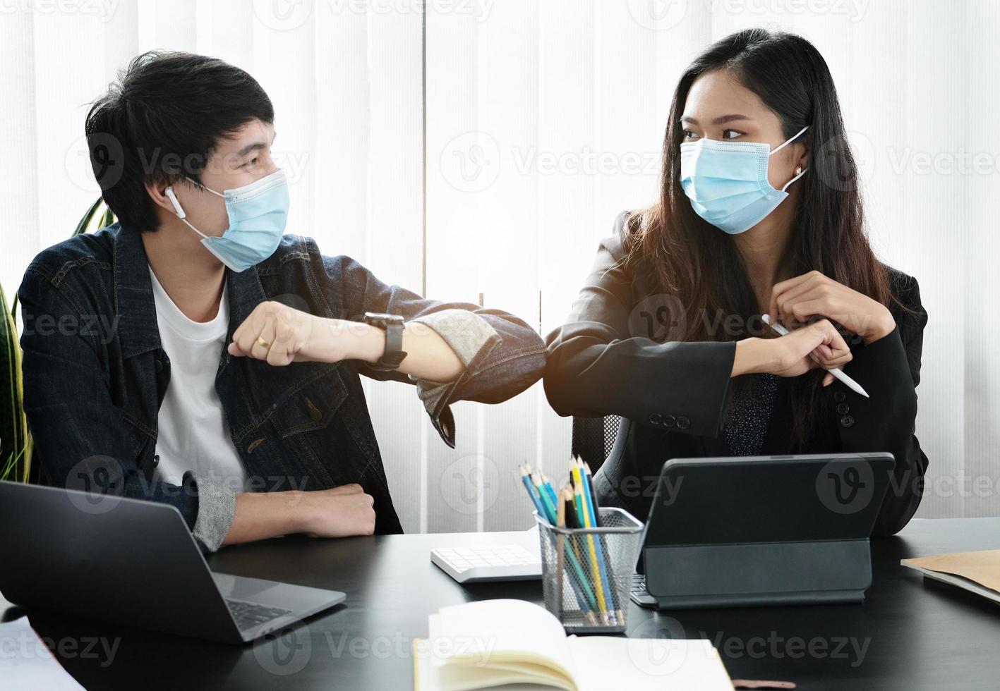 Two professionals bumping elbows with masks on photo