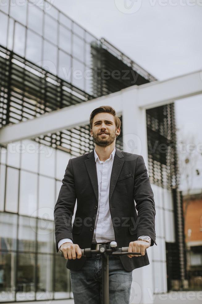 Business man riding an electric scooter by an office building photo