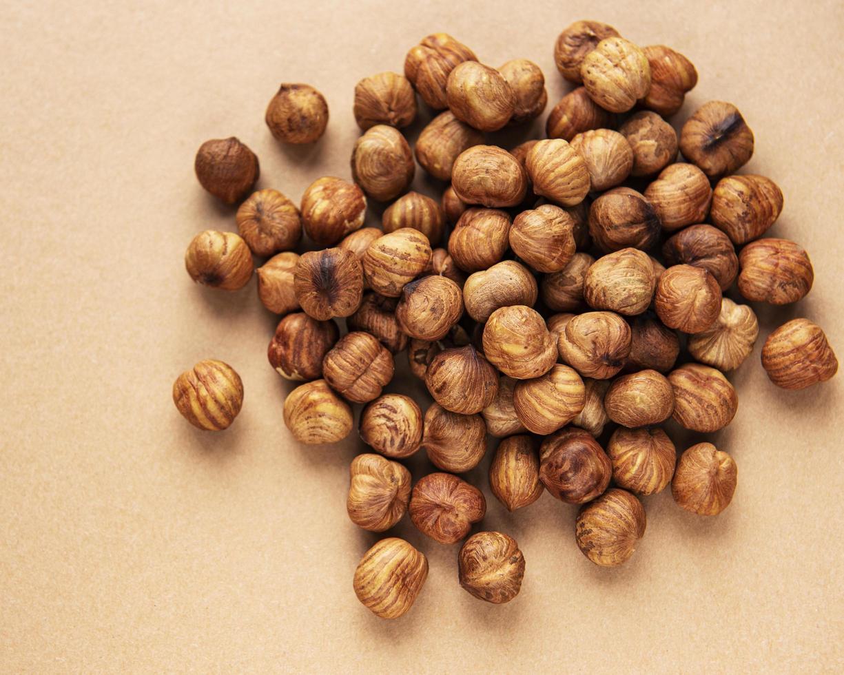 Peeled hazelnuts on brown background photo