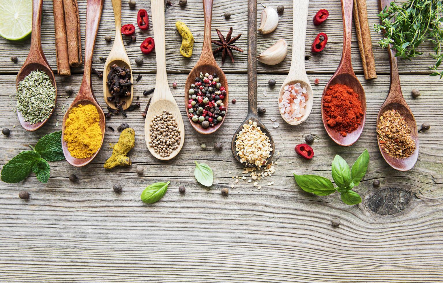 A selection of various colorful spices on a wooden table in spoons photo