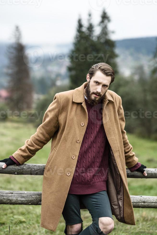 hombre con un abrigo marrón y pantalones rotos foto