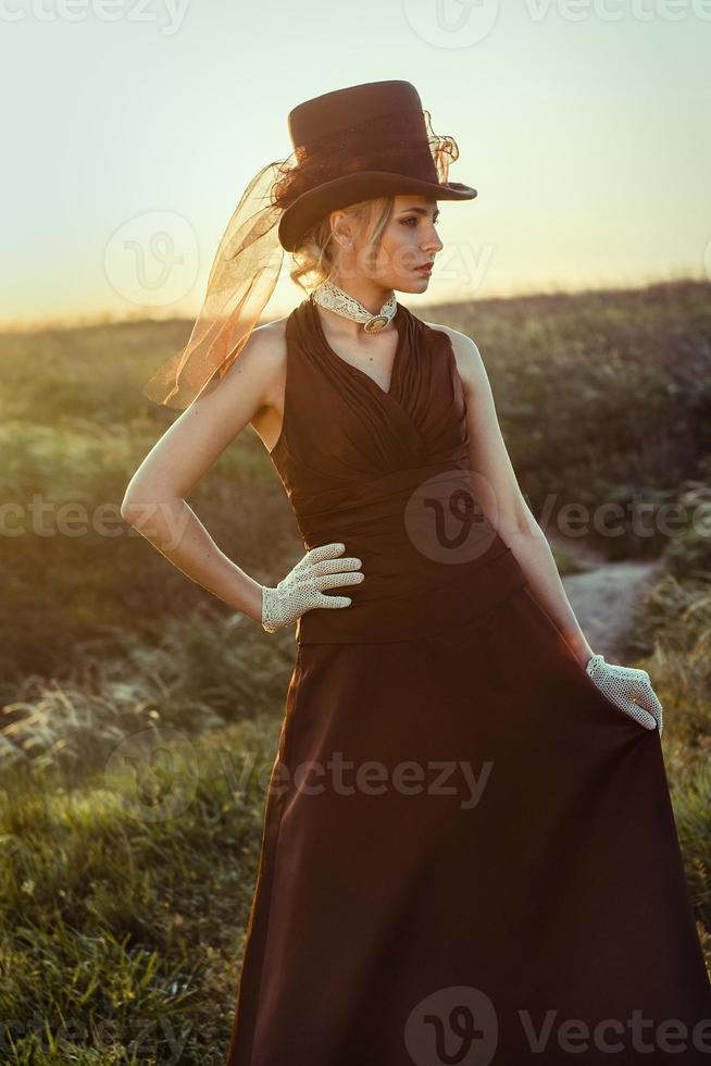 Joven rubia con un vestido vintage marrón y sombrero de copa foto