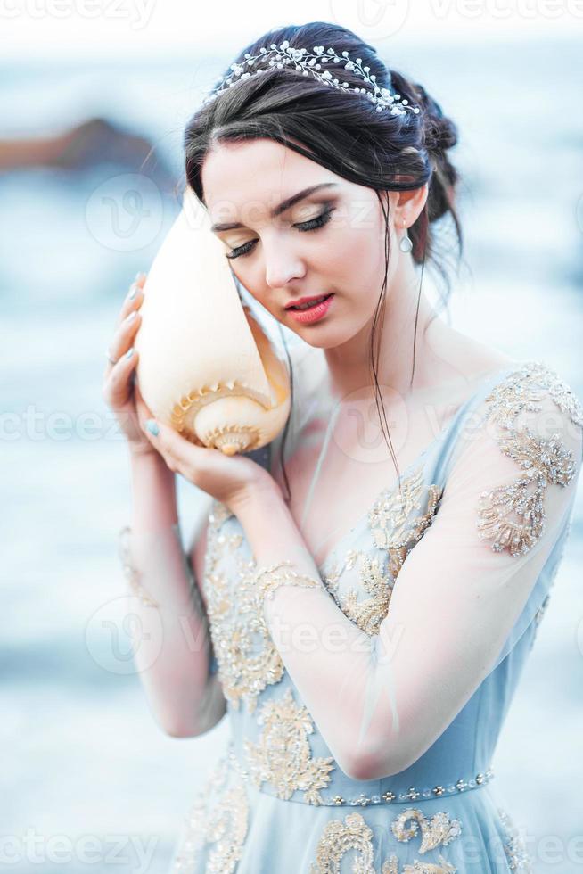 bride with a big shell on the beach photo