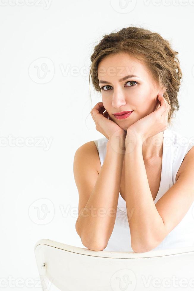 Chica alegre en una camiseta blanca y jeans azul oscuro en el estudio sobre un fondo blanco. foto