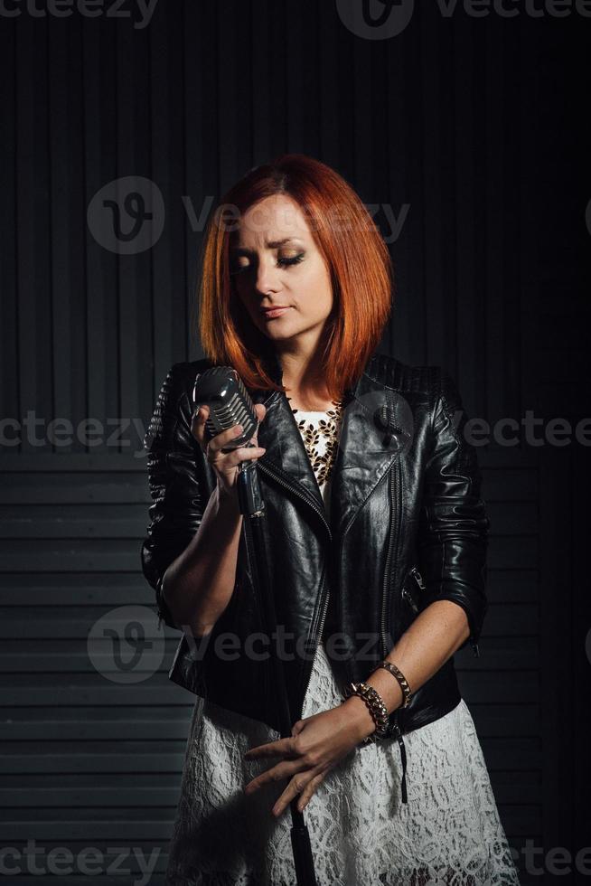 red haired girl in a black jacket and blue glasses photo