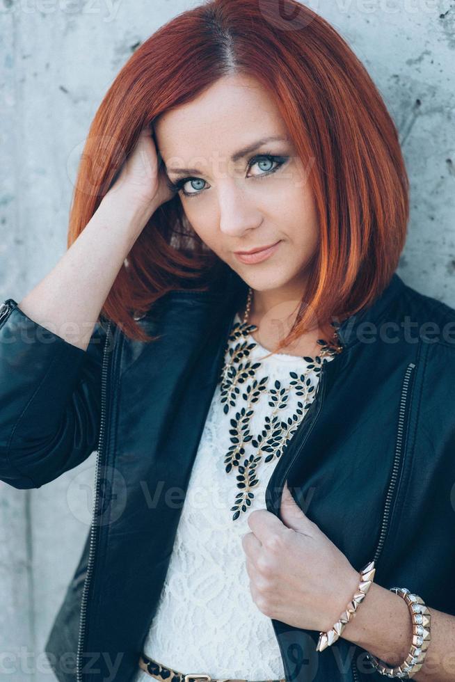 red haired girl in a black jacket and blue glasses photo