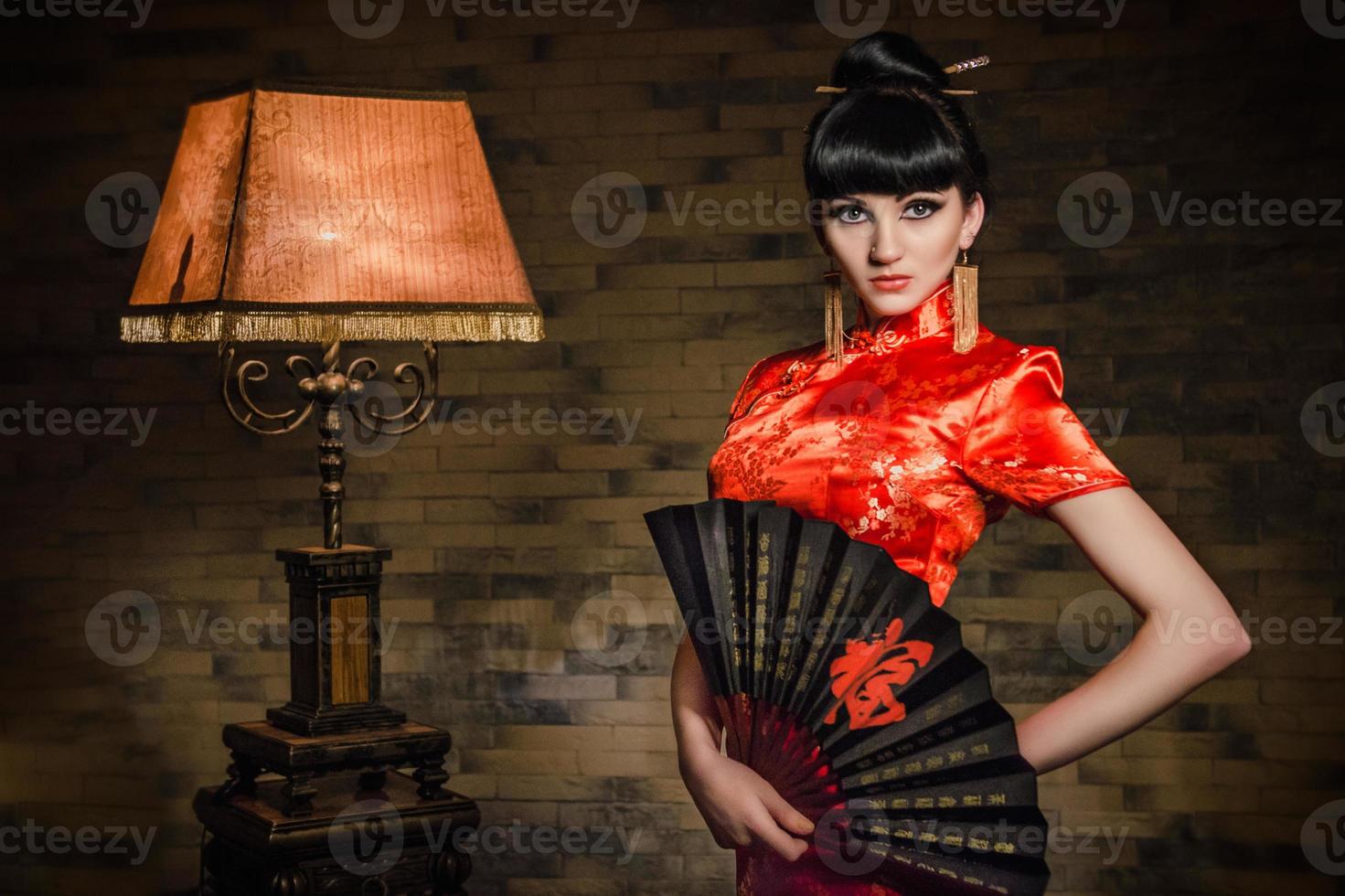 chica con un vestido rojo de seda japonesa qipao en una habitación oscura foto