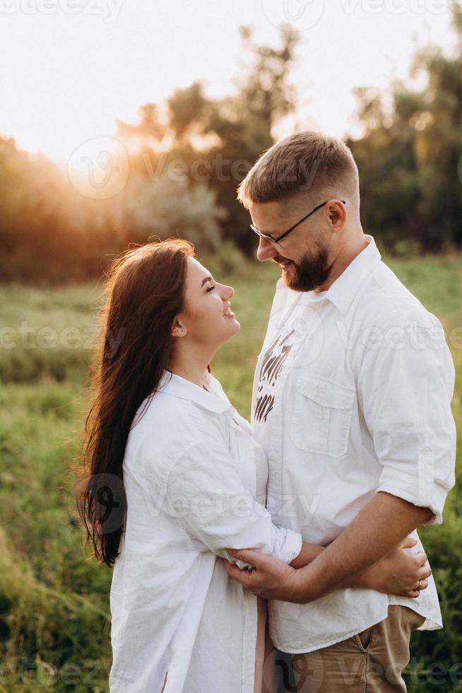 Pareja joven enamorada de un chico con barba y una chica de cabello oscuro con ropa clara foto