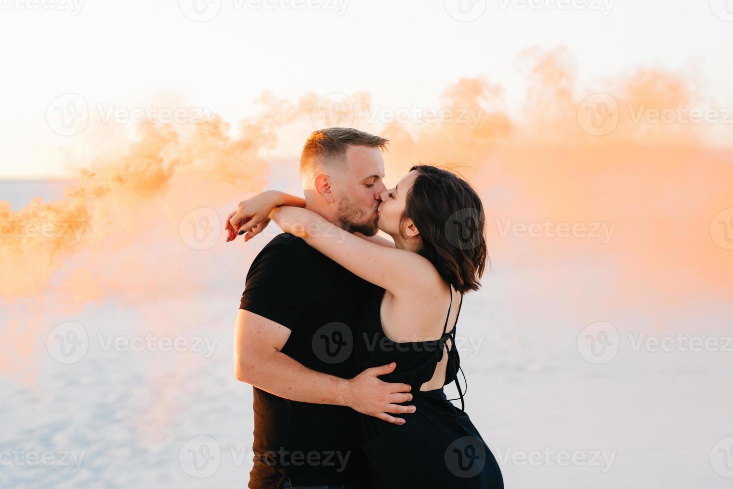 guy and a girl in black clothes hug and run on the white sand photo
