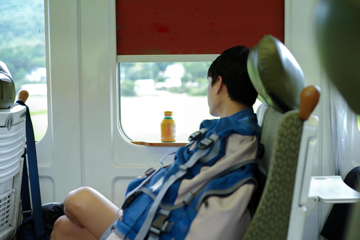 Retrato de hombre asiático durmiendo la siesta durante un viaje en tren. un hombre se sienta en el asiento de la ventana de un tren. foto