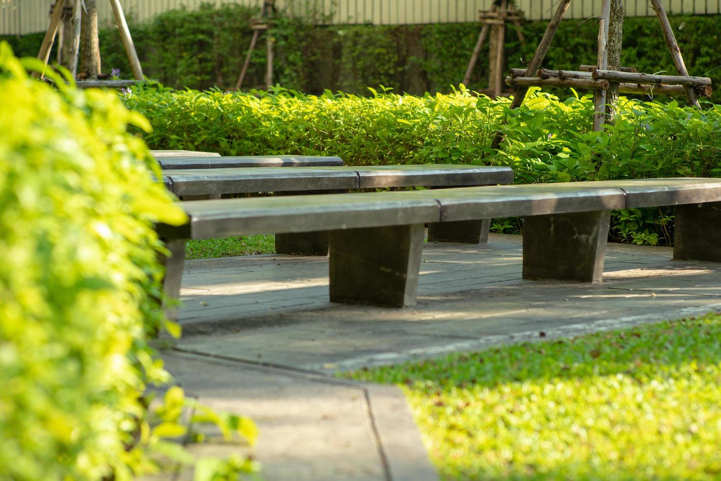 Selective focus of empty concrete benches in an outdoor park with blurred green bush in the background photo