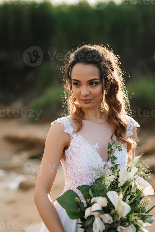 novia con un ramo de novia en la orilla del mar foto