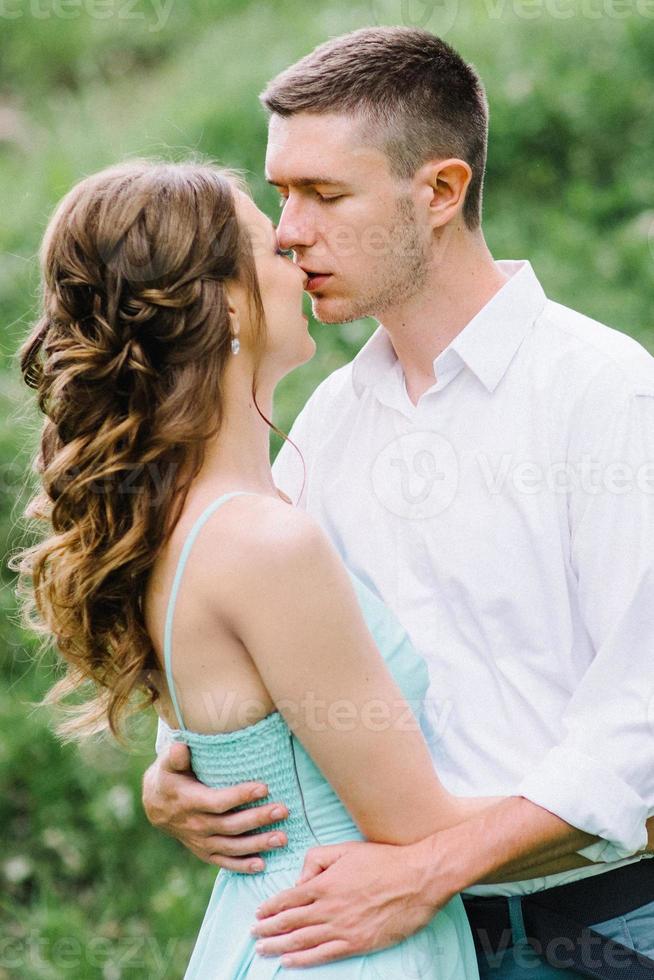 happy guy in a white shirt and a girl in a turquoise dress are walking in the forest park photo