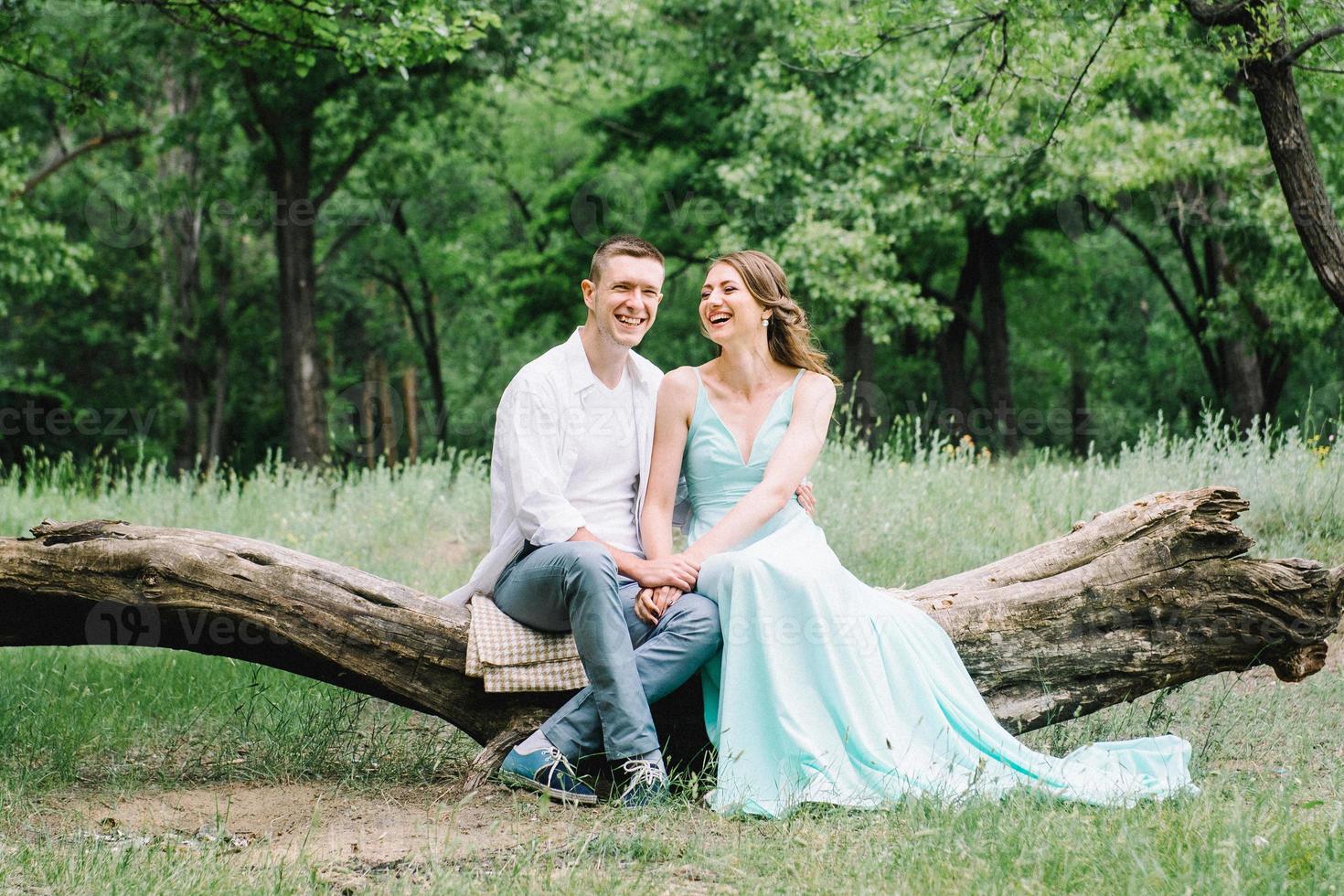 happy guy in a white shirt and a girl in a turquoise dress are walking in the forest park photo