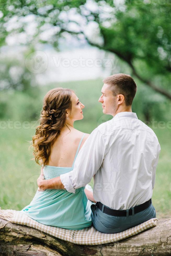 chico feliz con una camisa blanca y una chica con un vestido turquesa están caminando en el parque forestal foto