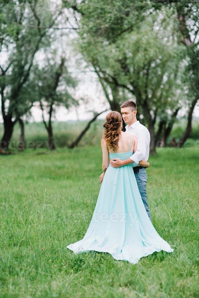 chico feliz con una camisa blanca y una chica con un vestido turquesa están caminando en el parque forestal foto