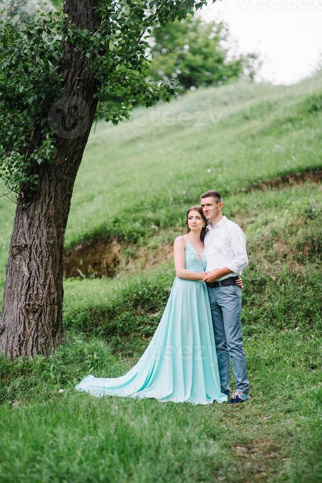 chico feliz con una camisa blanca y una chica con un vestido turquesa están caminando en el parque forestal foto