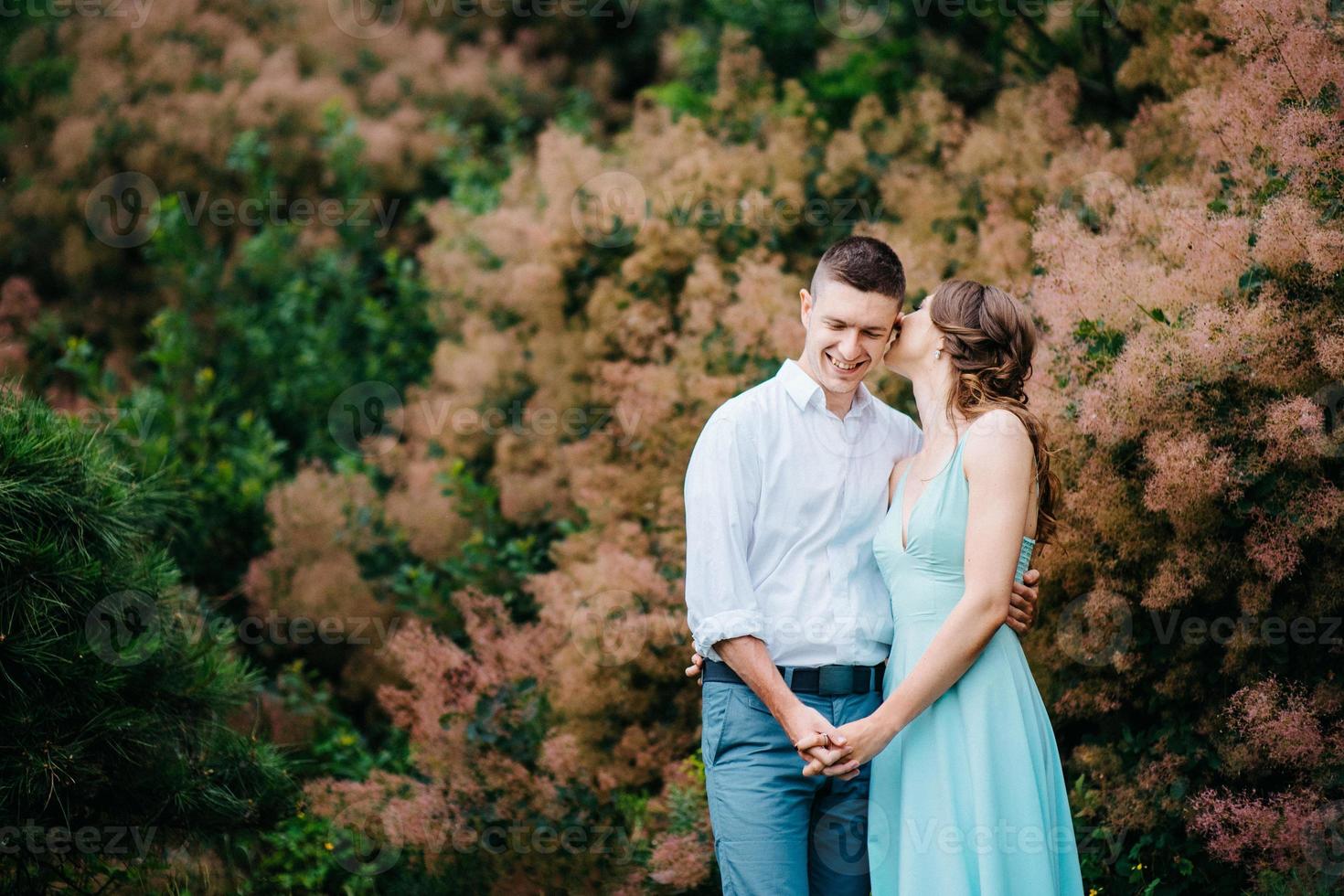 chico feliz con una camisa blanca y una chica con un vestido turquesa están caminando en el parque forestal foto