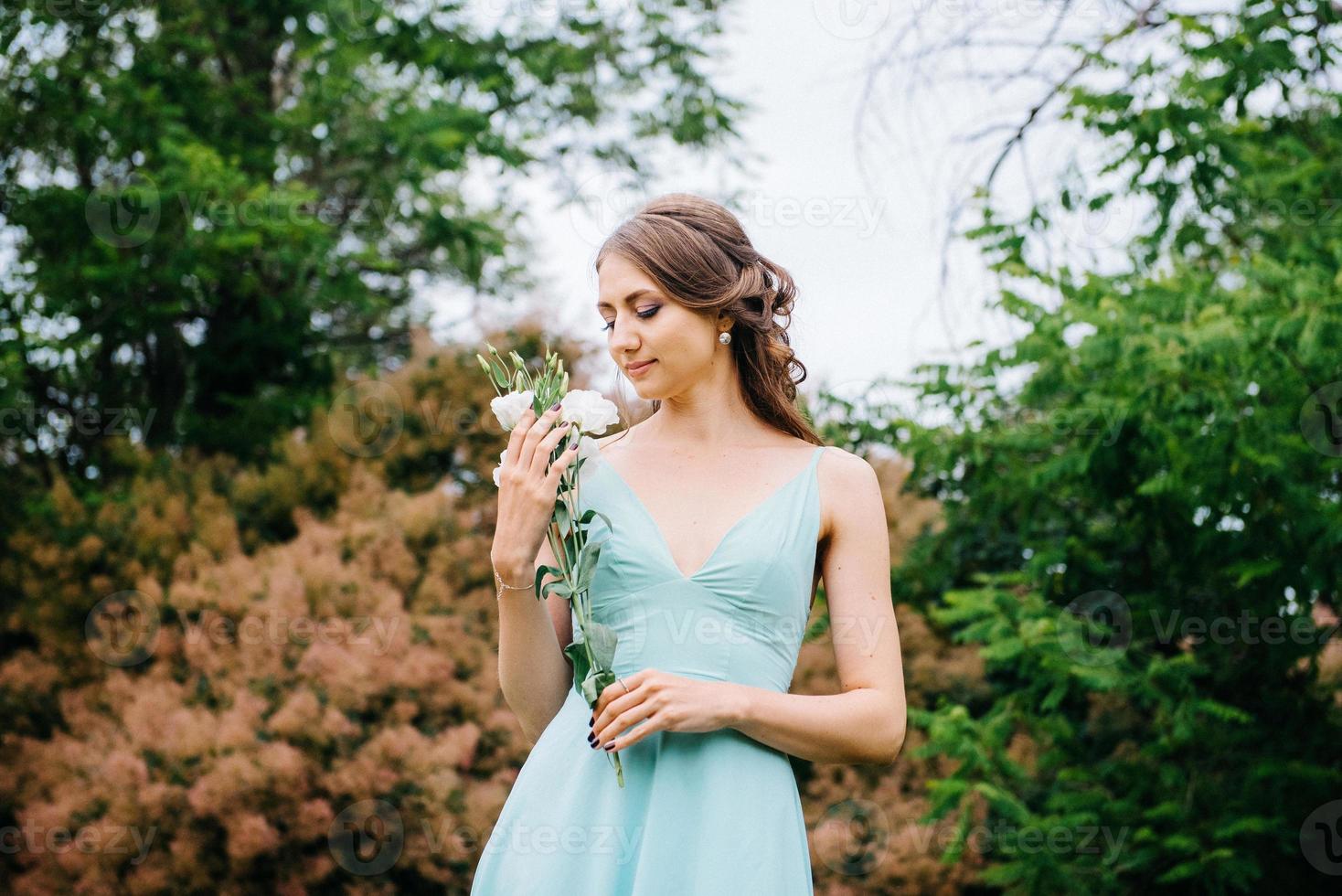 Happy girl in a turquoise long dress in a green park photo