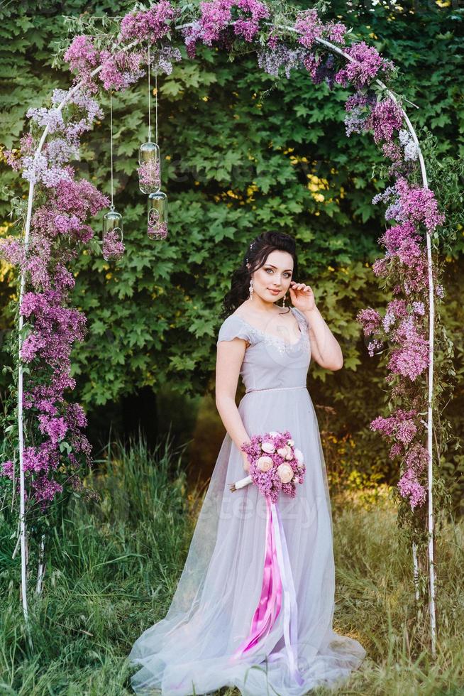 Retrato de una niña morena en un jardín de primavera de lilas en el arco foto