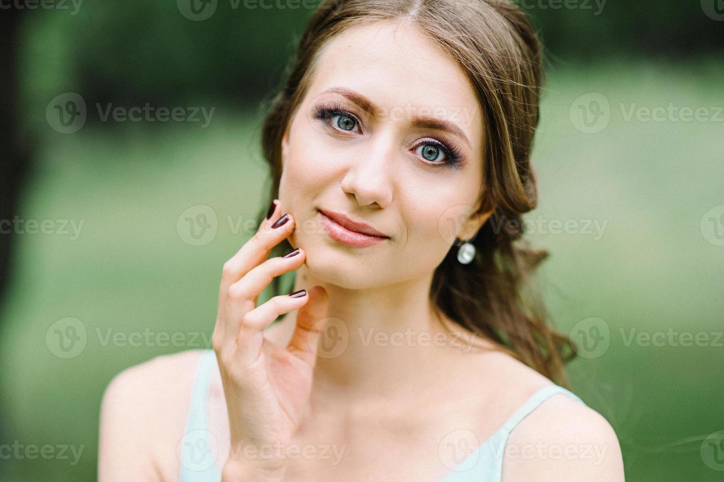 Happy girl in a turquoise long dress in a green park photo