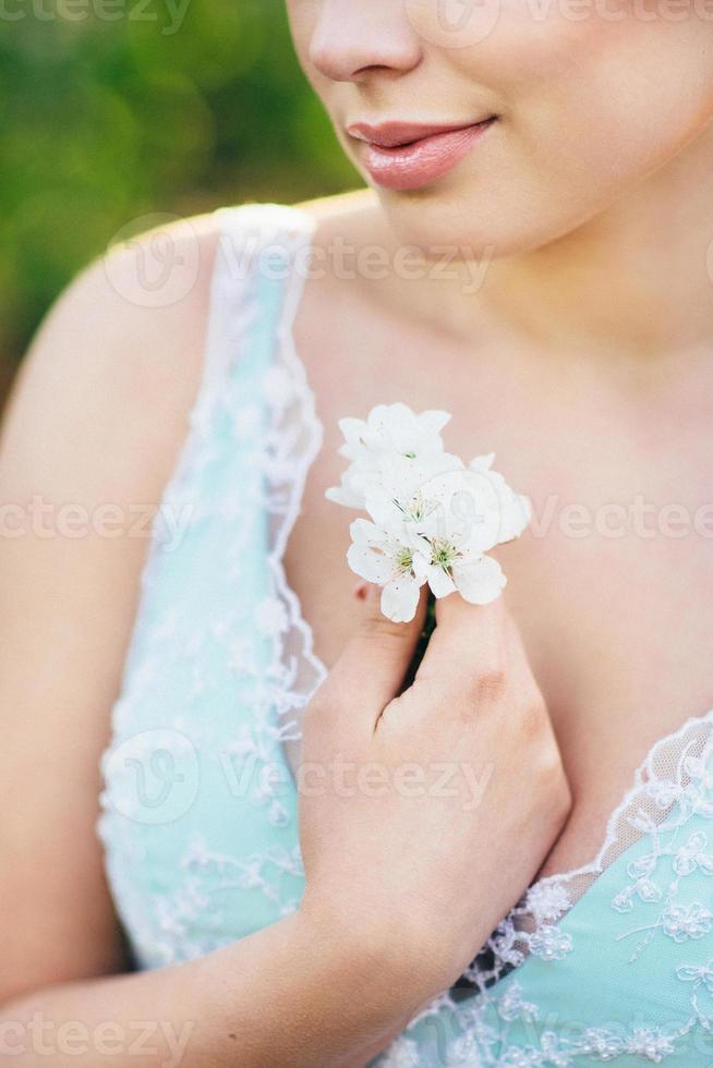 Chica morena con un vestido turquesa en el jardín de primavera foto