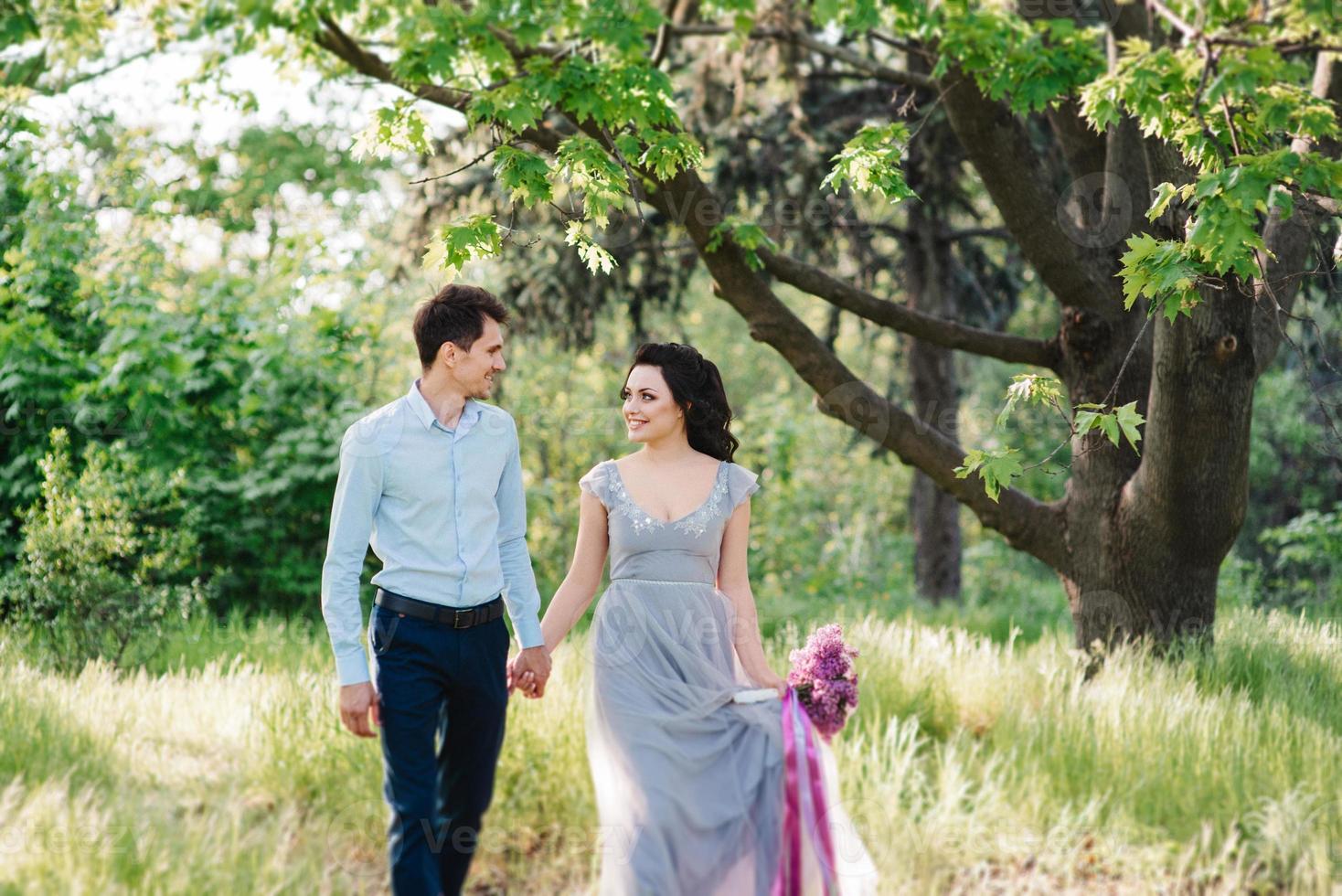 un chico y una chica caminan en el jardín de primavera de lilas foto