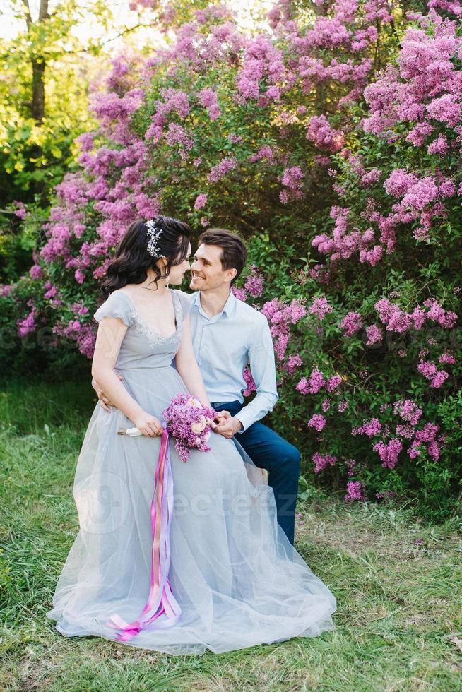 un chico y una chica caminan en el jardín de primavera de lilas foto