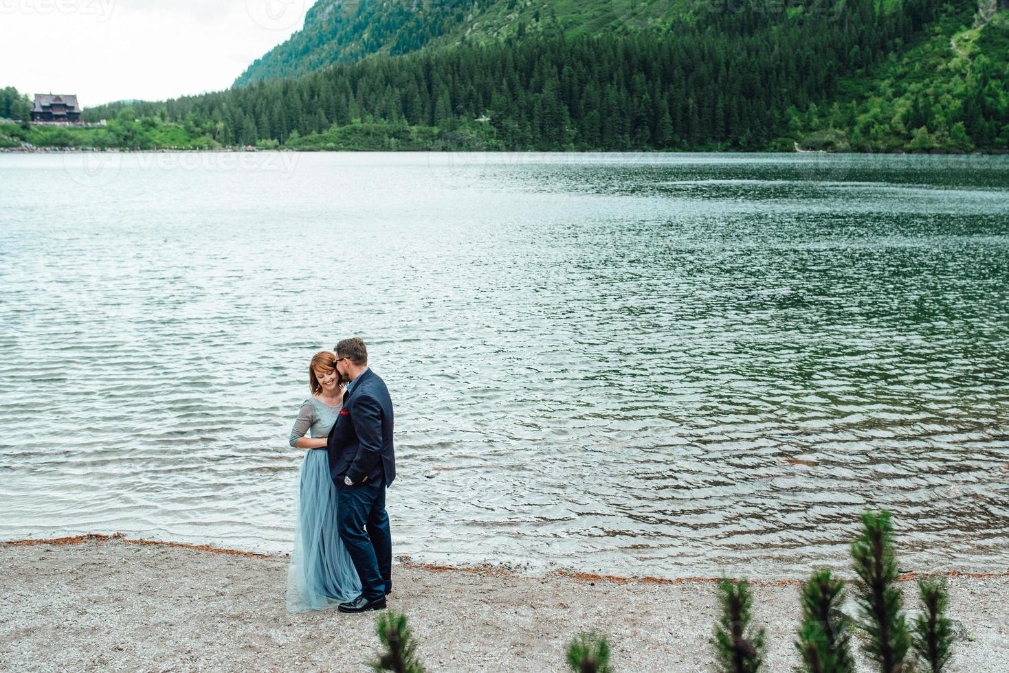 pareja joven en un paseo cerca del lago rodeado por las montañas foto