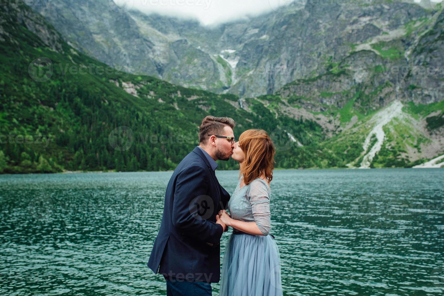 young couple on a walk near the lake surrounded by the mountains photo