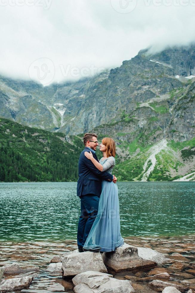 pareja joven en un paseo cerca del lago rodeado por las montañas foto