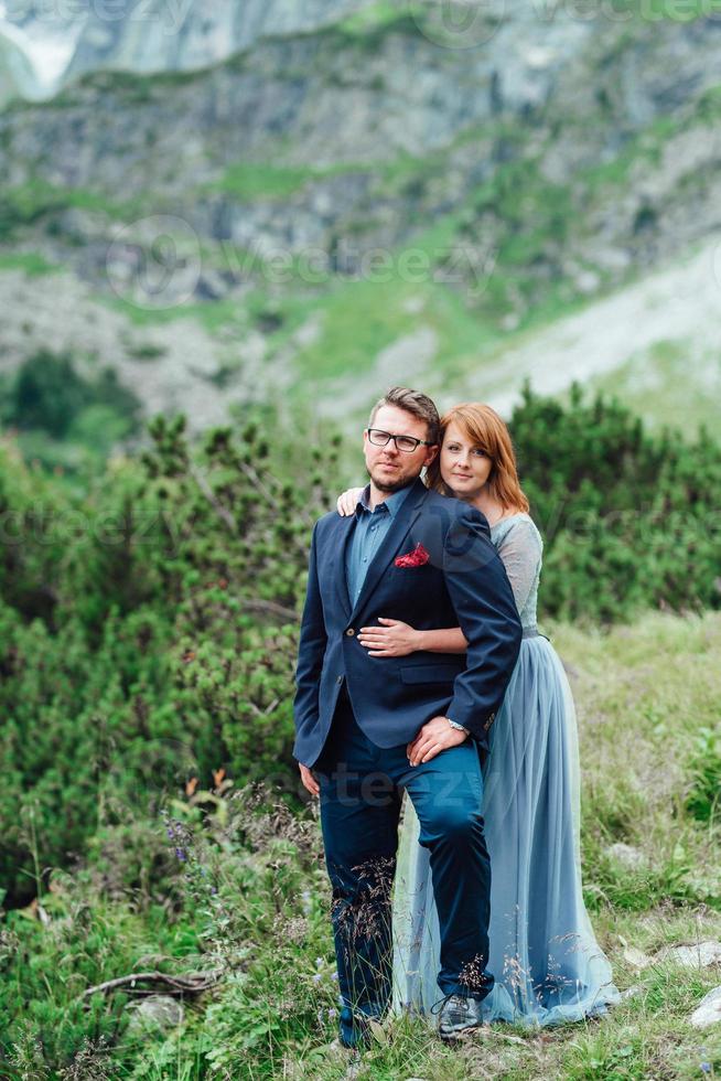 young couple on a walk near the lake surrounded by the mountains photo