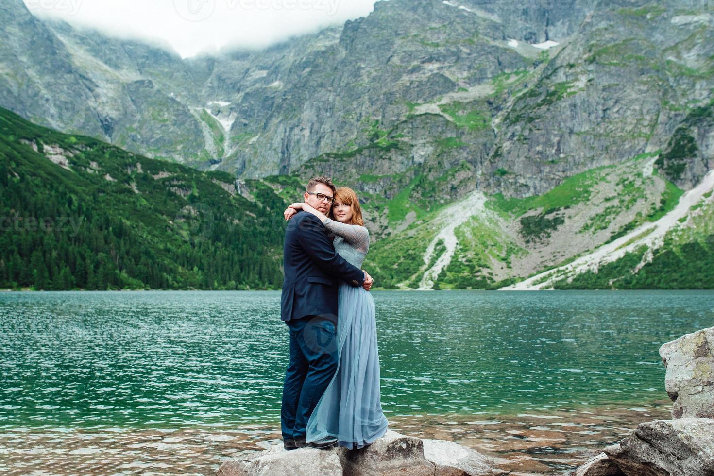 pareja joven en un paseo cerca del lago rodeado por las montañas foto