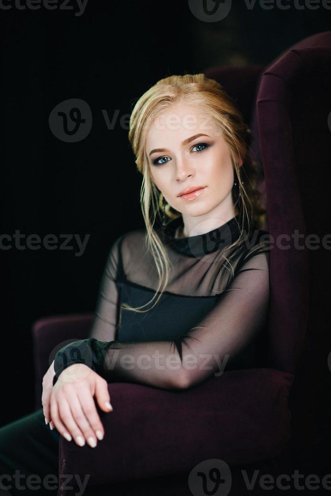 Blonde girl with blue eyes in a black dress photo