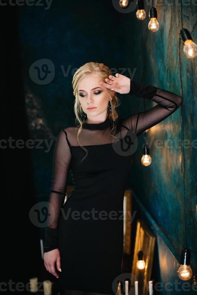 Blonde girl with blue eyes in a black dress photo